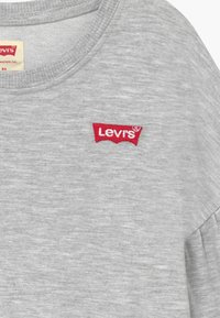 T-shirt en coton gris avec un col rond et un logo Levi's brodé en rouge sur la poitrine avec une légère texture.