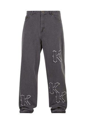 Jean gris coupe ample avec patches brodés usés en forme de lettre "K" sur la cuisse gauche, le genou droit et la cheville gauche.