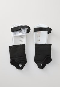 Weiße Kunststofffußstützen mit schwarzen Stoffummantelungen, elastischen Riemen und Belüftungsöffnungen. Enthält Produktetikett an einer Stütze.