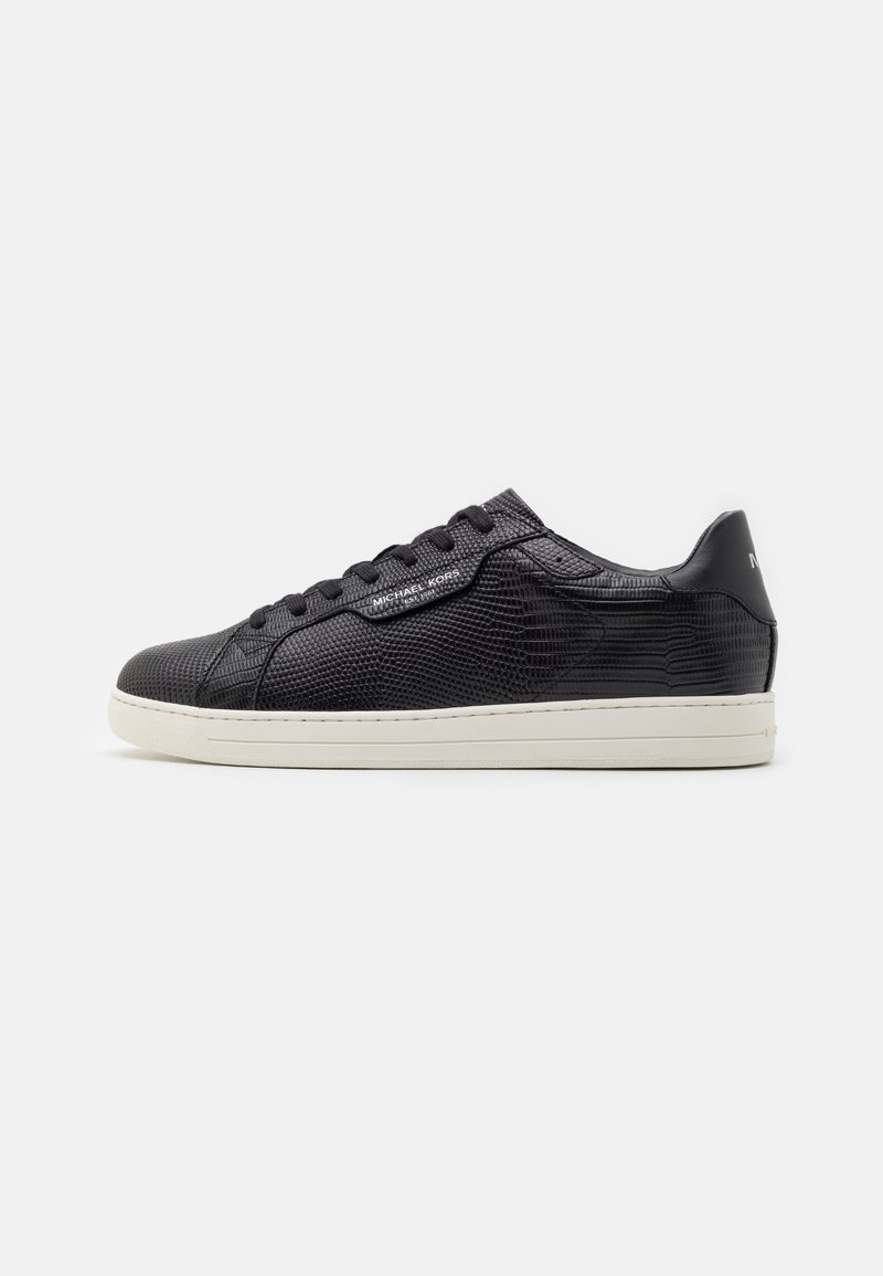 Baskets basses en cuir noir texturé avec lacets noirs et semelle blanche, logo latéral et patte de talon lisse.