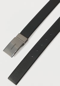 Črn teksturiran usnjen pas z šestimi nastavitvenimi luknjami in sijočo srebrno pravokotno zaponko, ki je gravirana z "VALENTINO."