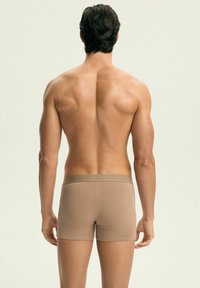Męskie brązowe bokserki z gładkiego materiału, z dopasowanym krojem i elastycznym pasem, pokazane z tyłu na neutralnym tle.