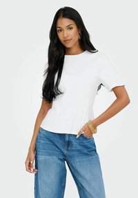 Vit kortärmad t-shirt med rund halsringning, parat med ljusblå raka jeans. Mjukt tyg med avslappnad passform.