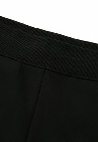 Zwarte joggingsbroek met een geribde tailleband en een soepele textuur, met een naadloos ontwerp en een getailleerde pasvorm langs het been.