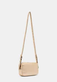 Praktična pravokutna torba za crossbody od mekanog, teksturiranog bež kože. Podesivi remen s zlatnim akcentima. Kompaktni dizajn s zatvaračem na munje.