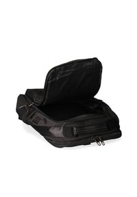 Zwarte laptoptas met een slanke, zachte stof buitenkant, ritssluiting en een lege binnenkant die een enkel compartiment toont.