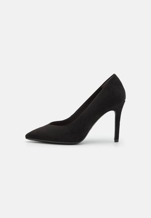 Sort ruskind stilletto-pumpe med spids tå og slank høj hæl, vist i sideprofil mod en hvid baggrund.
