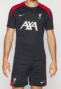 Svart atletisk tröja och shorts med röda accenter, med en vit Nike-logotyp och texten "AXA", samt Liverpool FC:s klubbemblem på shortsen.