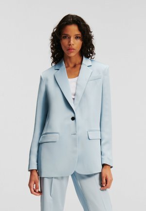 Light blue tailored blazer made from smooth fabric, featuring a single black button, two front pockets, and notched lapels.