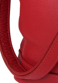 Rode leren handtas met een gladde textuur, een gebogen ontwerp en een stevige riem met gedetailleerde stiksels langs de randen.