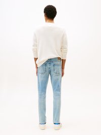 White knit sweatshirt, light blue denim jeans, white shoes with blue accents, shown from the back against a plain background.