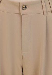 Beige broek met een gladde textuur, voorzien van een knoopsluiting aan de voorkant en een zijzak. Op maat gemaakte pasvorm met rechte pijpen.