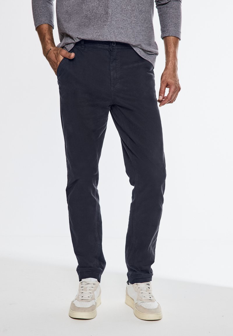 Námořnické bavlněné chinos kalhoty se slim fit, které mají přední kapsy a knoflíkový zapínání, v kombinaci s bílými a béžovými teniskami.