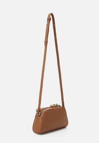 Hnedá kožená crossbody taška s oblým tvarom, nastaviteľným ramienkom a zlatými doplnkami, vybavená zipsovým uzáverom a hladkým povrchom.
