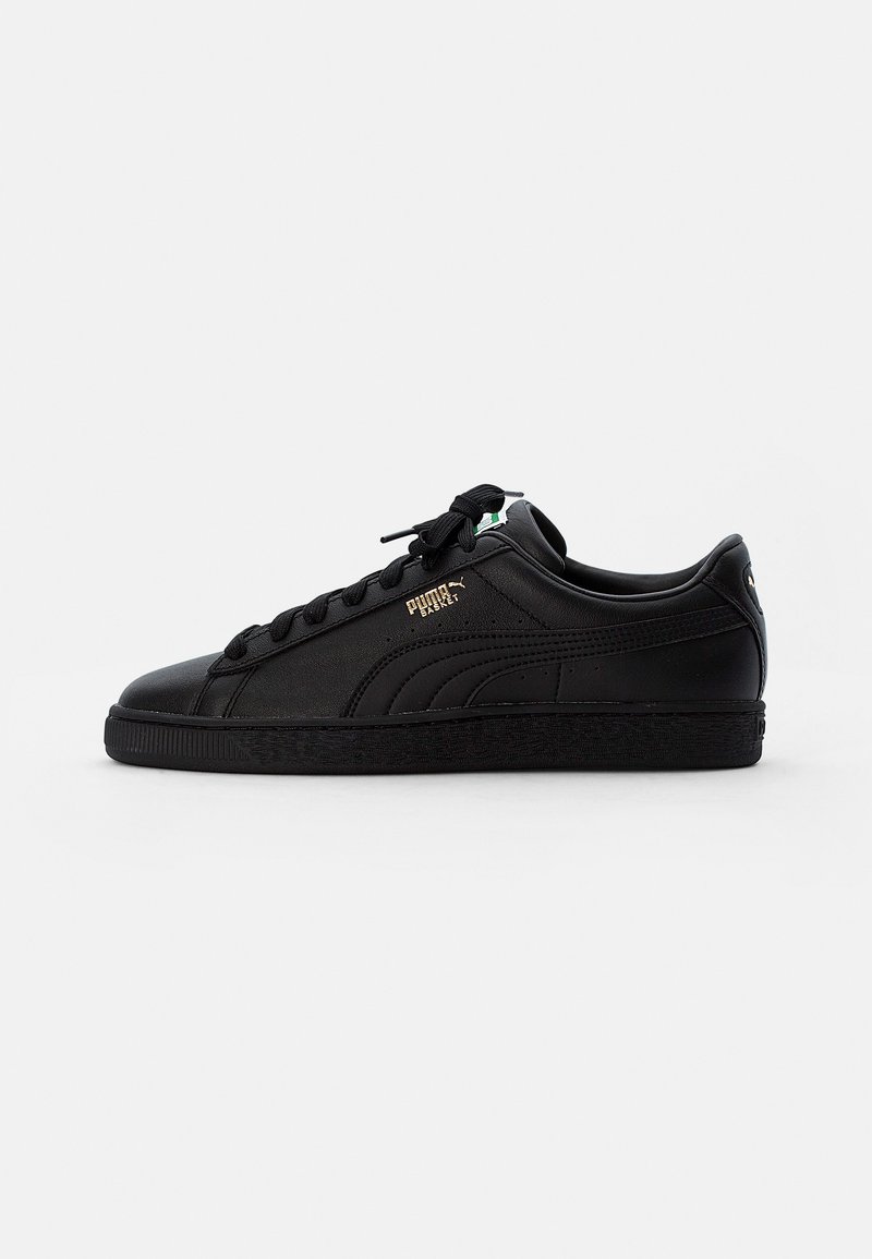 Zapatillas de cuero negro con una superficie texturizada, presentan cordones redondos, un logotipo grabado y una suela de goma con un patrón sutil.