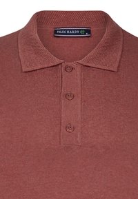Polo de manga corta en color óxido, con cuello texturizado, tapeta de tres botones y tejido de punto con sutiles detalles de canalé.