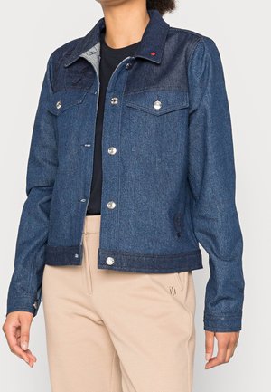 Mörkblå denimjacka med två bröstfickor, silverfärgade tryckknappar och en kontrastfärgad krage. Har en lätt blekning och broderad logotyp.