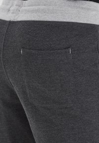 Charcoal gray sweatpants with a ribbed gray waistline, featuring a back pocket and a soft, textured fabric.