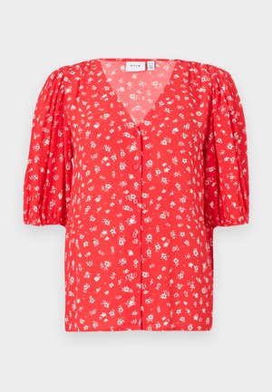 Chemisier rouge à fleurs avec col en V, manches courtes bouffantes, fermeture à boutons sur le devant, et tissu léger texturé.