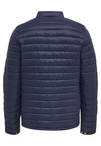 Mörkblå puffjacka med kviltat mönster, med horisontella sektioner, ståkrage och tryckknappar vid ärmarna.