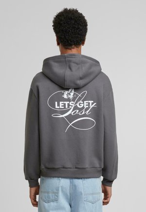 Grå hoodie med frontlomme og snøre i hætten. Har hvid tekst "LAD OS GÅ TABT" og et sommerfugle-grafik på ryggen.