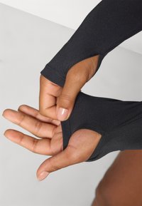 Black long-sleeve top with thumb holes, made of smooth stretchy fabric. Features fitted sleeves and clean stitching.