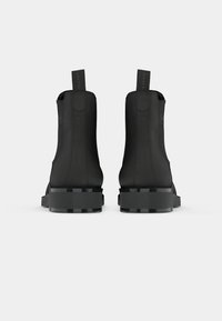 Las botas negras hasta el tobillo tienen una textura suave, punta redonda y un tacón grueso. Los paneles laterales elásticos y las pestañas de tirón mejoran la funcionalidad.