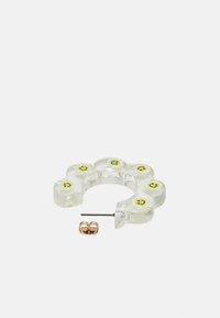 Brinco transparente em forma de flor com acentos de carinha sorridente amarela, apresentando um pino metálico. Inclui um pequeno brinco de argola dourada.