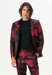 Schwarzes Anzug mit rotem Blumenmuster, bestehend aus einem taillierten Sakko und passenden Hosen. Wird über einem schwarzen Top getragen, das eine glatte Textur und ein strukturiertes Design aufweist.