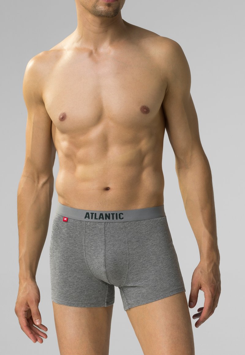 Szare bokserki z bawełny elastycznej z logo w pasie, o dopasowanym kroju i gładkiej teksturze, noszone przez modela.