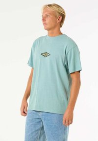 Hellblaues Baumwoll-T-Shirt mit kurzen Ärmeln, das ein kleines Logo in der Mitte aufweist. Der Schnitt ist lässig, mit einem runden Ausschnitt und einem schlichten Design.