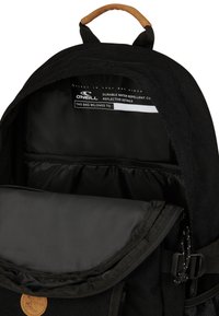 Intérieur d'un sac à dos noir avec une doublure résistante à l'eau, texture lisse et poches organisatrices. Comprend une étiquette pour la personnalisation.