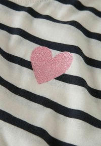 Gestreifter Stoff in Weiß und Marineblau, mit einem pinken Glitzerherz als Akzent. Die Textur ist weich, mit sichtbarer Stoffstruktur und Nahtdetails.