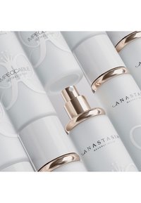 Witte sprayflacons met gouden doppen, met de tekst "Impeccable Setting Spray" en "Anastasia Beverly Hills" in zwarte letters.
