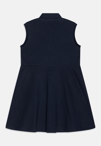 Tengerészkék ujjatlan ruha, galléros dekoltázzsal, testhez simuló felsőrészsel és bővülő szoknyával. Puha, textúrált anyagból készült.