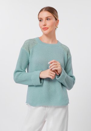 Lys blå ribbet genser med blonder på skuldrene; rund hals og lange ermer, med en avslappet passform og splitt i kanten.