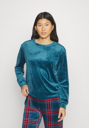 Teal fluwelen top met lange mouwen, een ronde hals, een zachte textuur en een ontspannen pasvorm, gecombineerd met een geruite broek in rode en groene tinten.