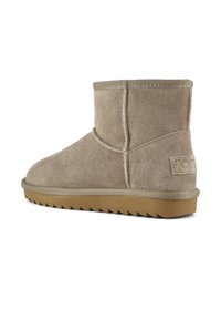 Stivaletti in suede beige alla caviglia con punta arrotondata e suola piatta in gomma. Presentano cuciture laterali e una targhetta testurizzata con marchio sul tallone.