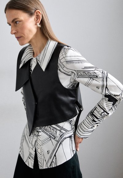 Chaleco de cuero negro sobre una camisa blanca con patrones de arte lineal en negro. Presenta un gran cuello y detalles de botones en la camisa.