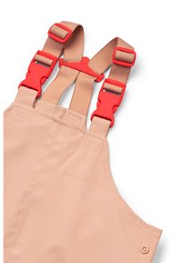 Μπεζ αδιάβροχες φόρμες με ρυθμιζόμενους κόκκινους πλαστικούς ιμάντες και ραμμένο λογότυπο. Λείος υφής με λειτουργικά μεταλλικά στοιχεία.