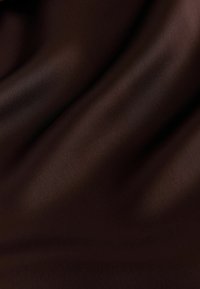 Tissu brun foncé avec une texture lisse et douce, et des plis délicats créant des ombres et des reflets subtils.