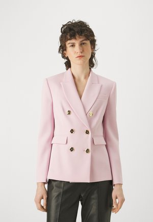 Blazer doppiopetto in morbido tessuto rosa con bottoni dorati, rever a punta e tasche anteriori. Abbinato a pantaloni in pelle nera.