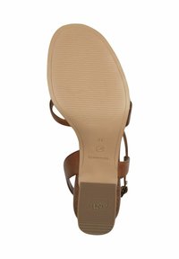 Semelle de sandale marron avec surface en caoutchouc texturé. Présente une forme contournée, un branding subtil et des sangles réglables pour un ajustement sécurisé.