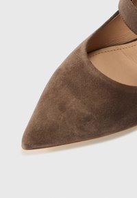 Καφέ σουέτ παπούτσι με μυτερή μύτη και μία λουρίδα στο πάνω μέρος, με λεία εσωτερική επιφάνεια και απαλή υφή.