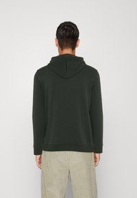 Felpa verde scuro con cappuccio, maniche lunghe e orlo a coste. La vista posteriore mostra una texture liscia e un design semplice senza loghi visibili.