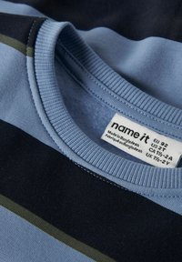 Col de chemise à rayures bleues et noires avec une étiquette de marque « name it » indiquant la taille et les détails d'origine cousue à l'intérieur.