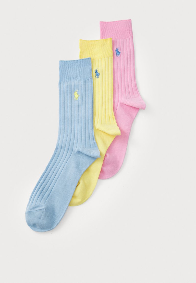 Trois paires de chaussettes en coton côtelé de couleur bleu clair, jaune et rose, arborant des accents de logo brodé sur chacune.