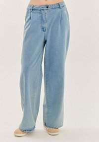 Svetlomodré džínsové nohavice so širokým strihom, vybavené zapínaním na gombík, záhybmi a prešitými detailmi vreciek. Hladká textúra.