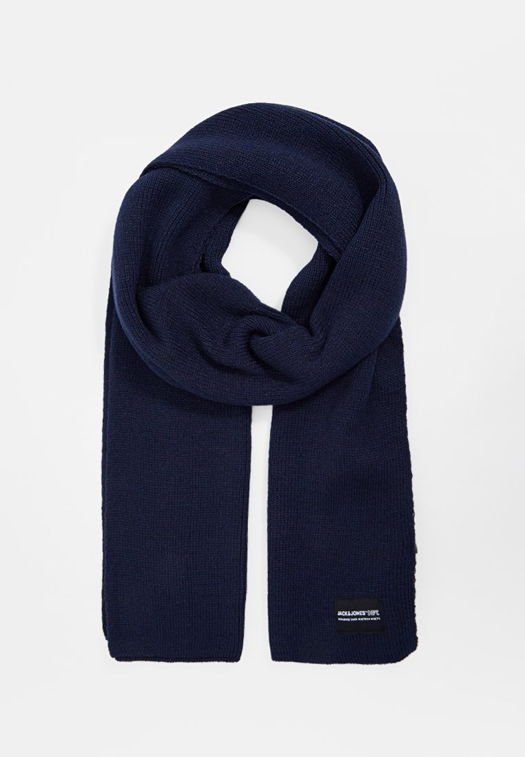 Dunkelblauer gestrickter Schal mit einem Schlaufenmuster. Strukturiert Oberfläche und ein kleines Logo-Patch in der unteren Ecke. Weiches Stoffmaterial.