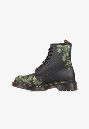 Botte en cuir noir à lacets avec coutures jaunes et motifs de feuilles tropicales vertes aux zones des orteils et du talon.